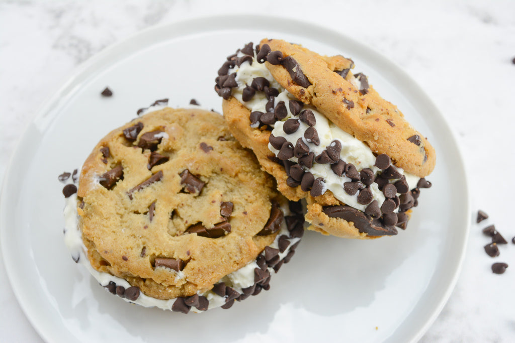 Two ice cream sandwiches sit on a white plate with chocolate chips surrounding.