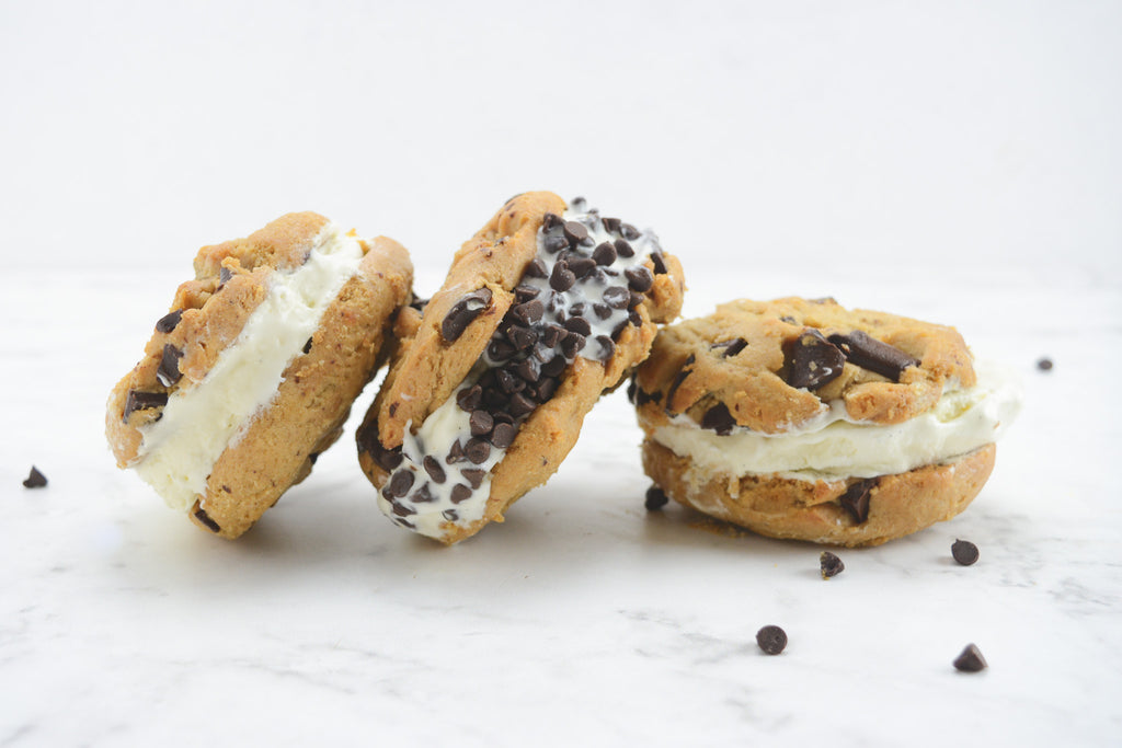 White background with loaf pan filled with three ice cream sandwiches that have chocolate chips around the edges.