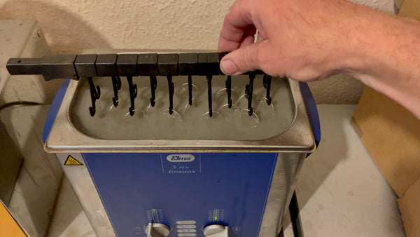 Multiple silver rings immersed in an Elma ultrasonic cleaner at Roberts & Co, sparkling as they're cleaned.