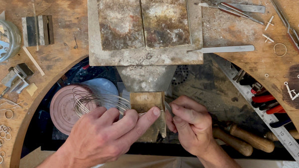 Intense focus on a silver wire being filed by a Roberts & Co artisan, the first step in the ring creation process.