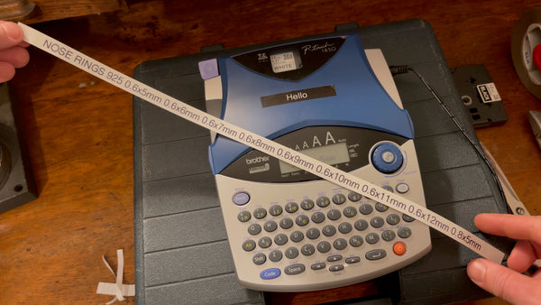 Brother P-Touch machine printing a label with black text on white tape