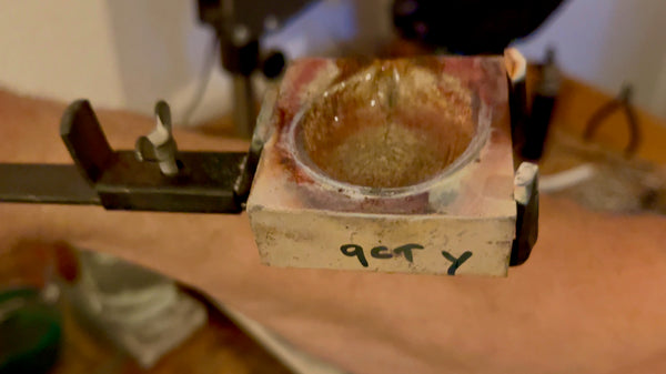 A crucible labeled with '9ct Y' using a sharpie, denoting the type of gold contained and ready for the melting process.