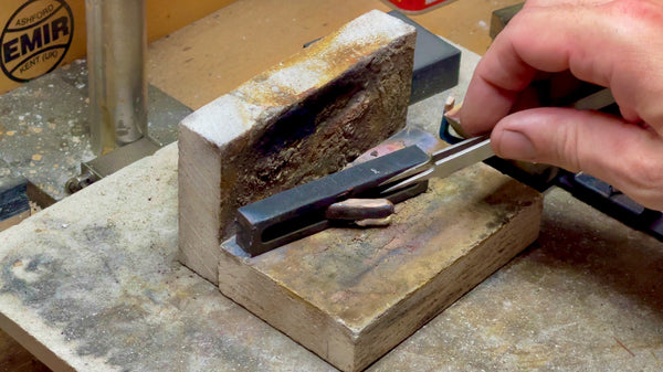 The process of carefully removing a newly formed gold ingot from its graphite mold, illustrating success and craftsmanship.