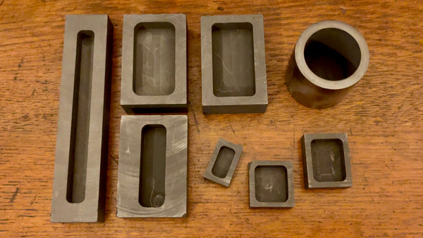 An assortment of graphite ingot molds in various sizes displayed together.