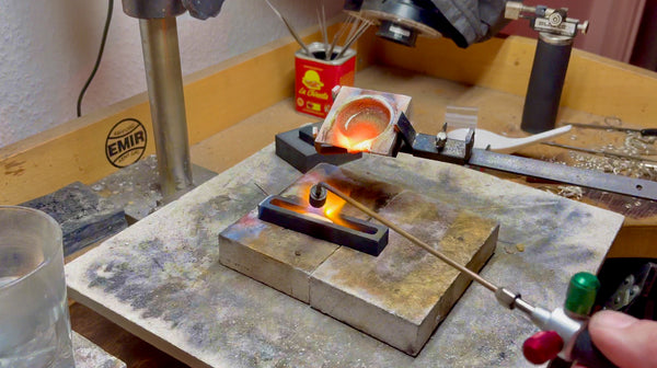 A freshly cast gold ingot nestling in the secure confines of a graphite ingot mold, showcasing the immediate aftermath of the pouring process.