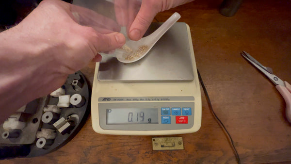 Precision weighing of 10 grams of gold on jeweler scales for ingot crafting.