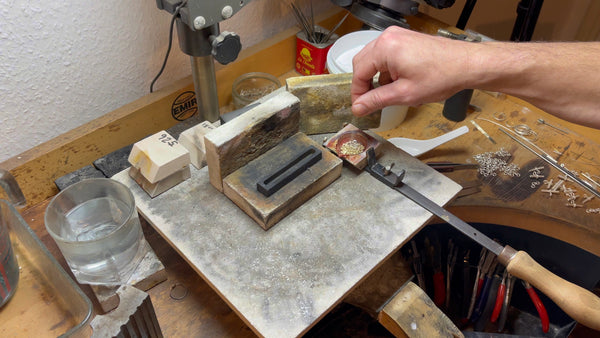 Borax flux being applied to gold before melting, ensuring purity and quality