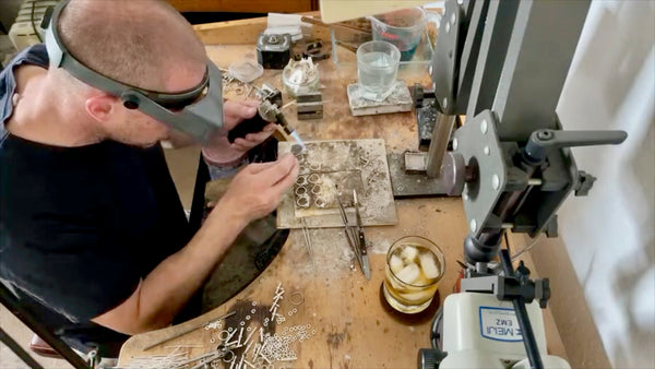 Carefully soldering rings together under a focused light.