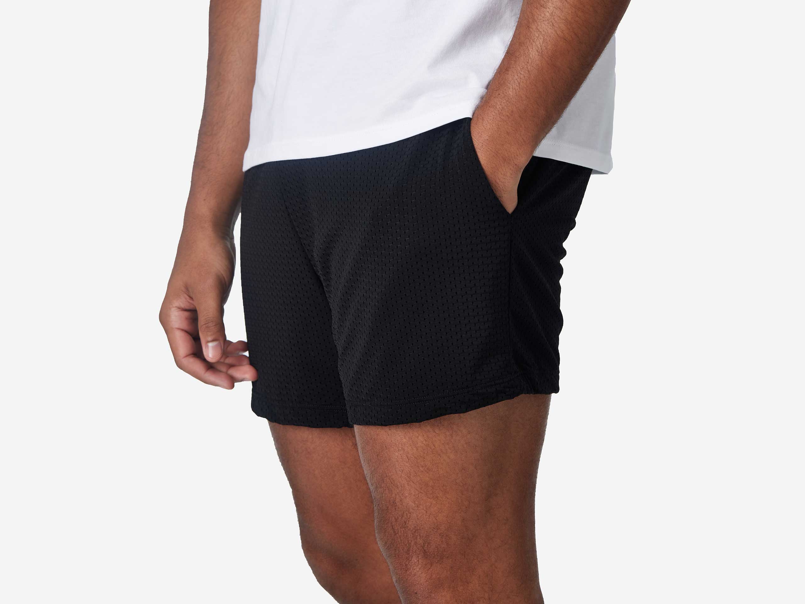 Close up of man wearing black mesh short with hand in pocket.