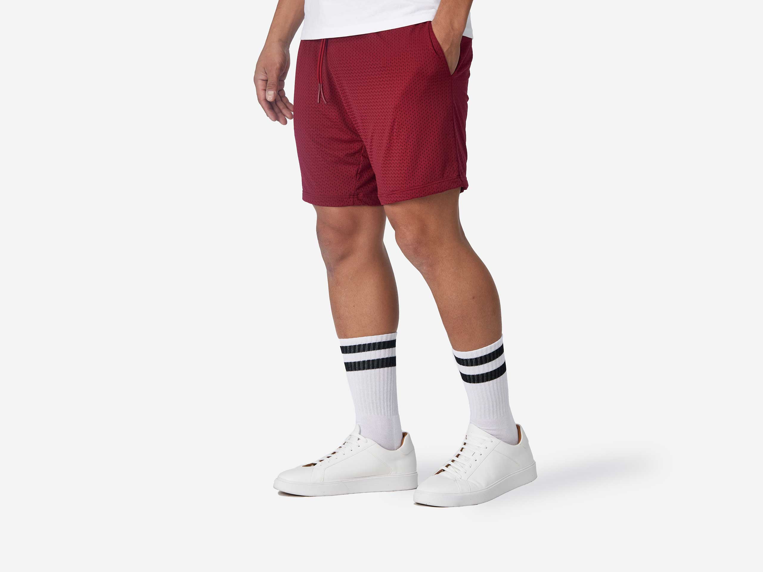 Side view shot of man wearing burgundy lounge short with hand in pocket.