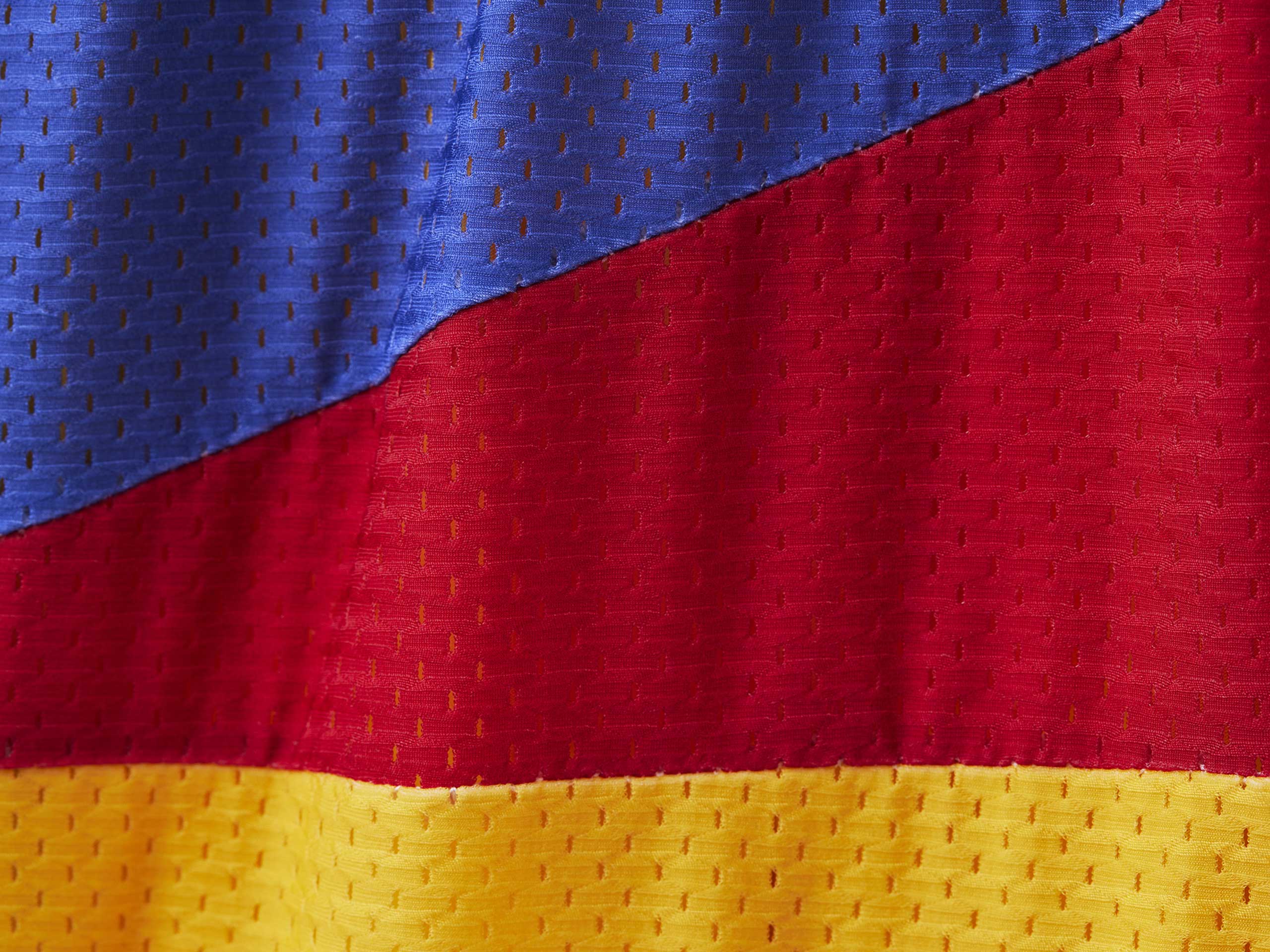 Close up detail shot of mesh material for Sunfish lounge short which is blue, red and mustard.