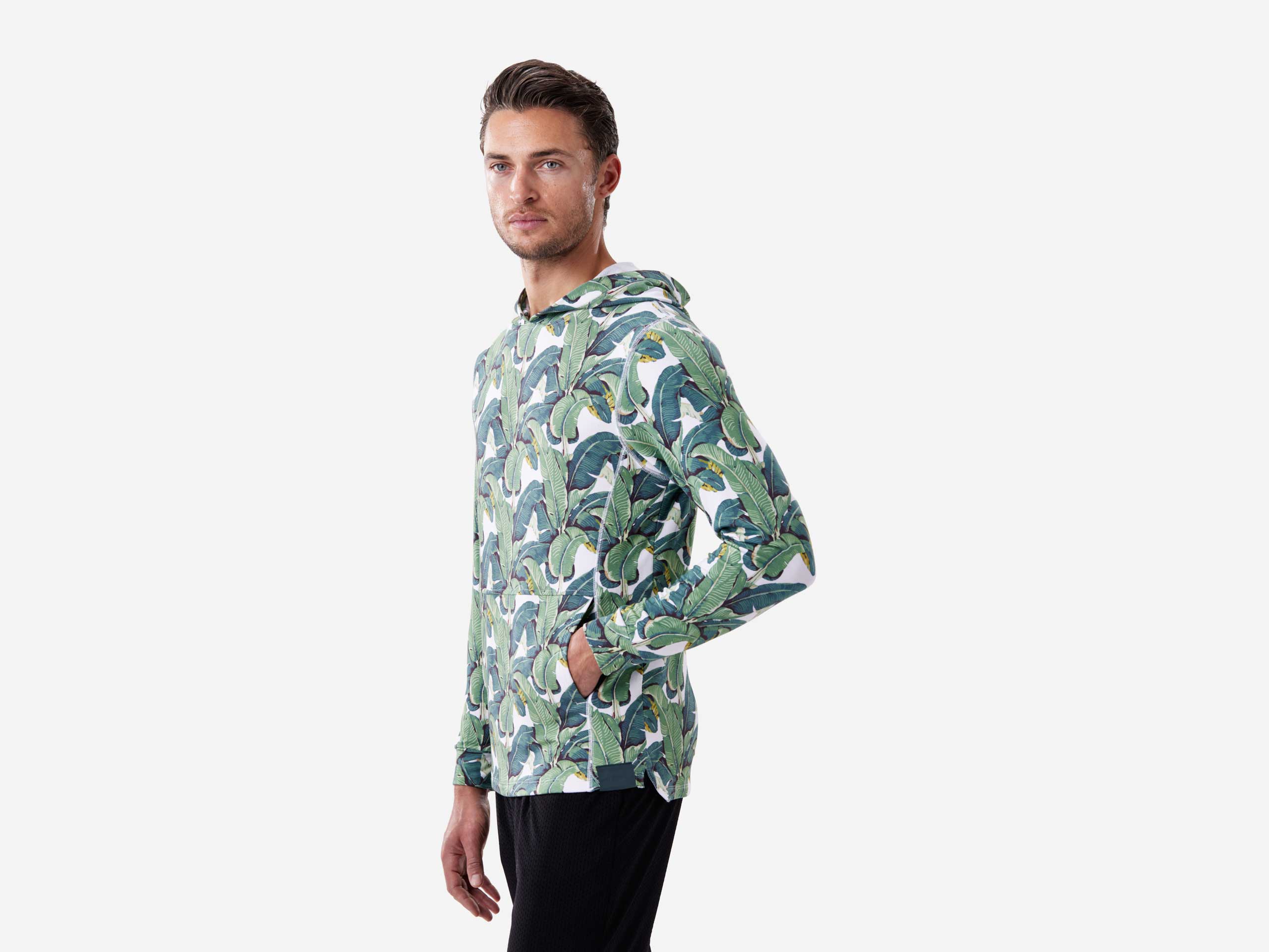 Side image of man with hand in pocket wearing palms print lounge hoodie.