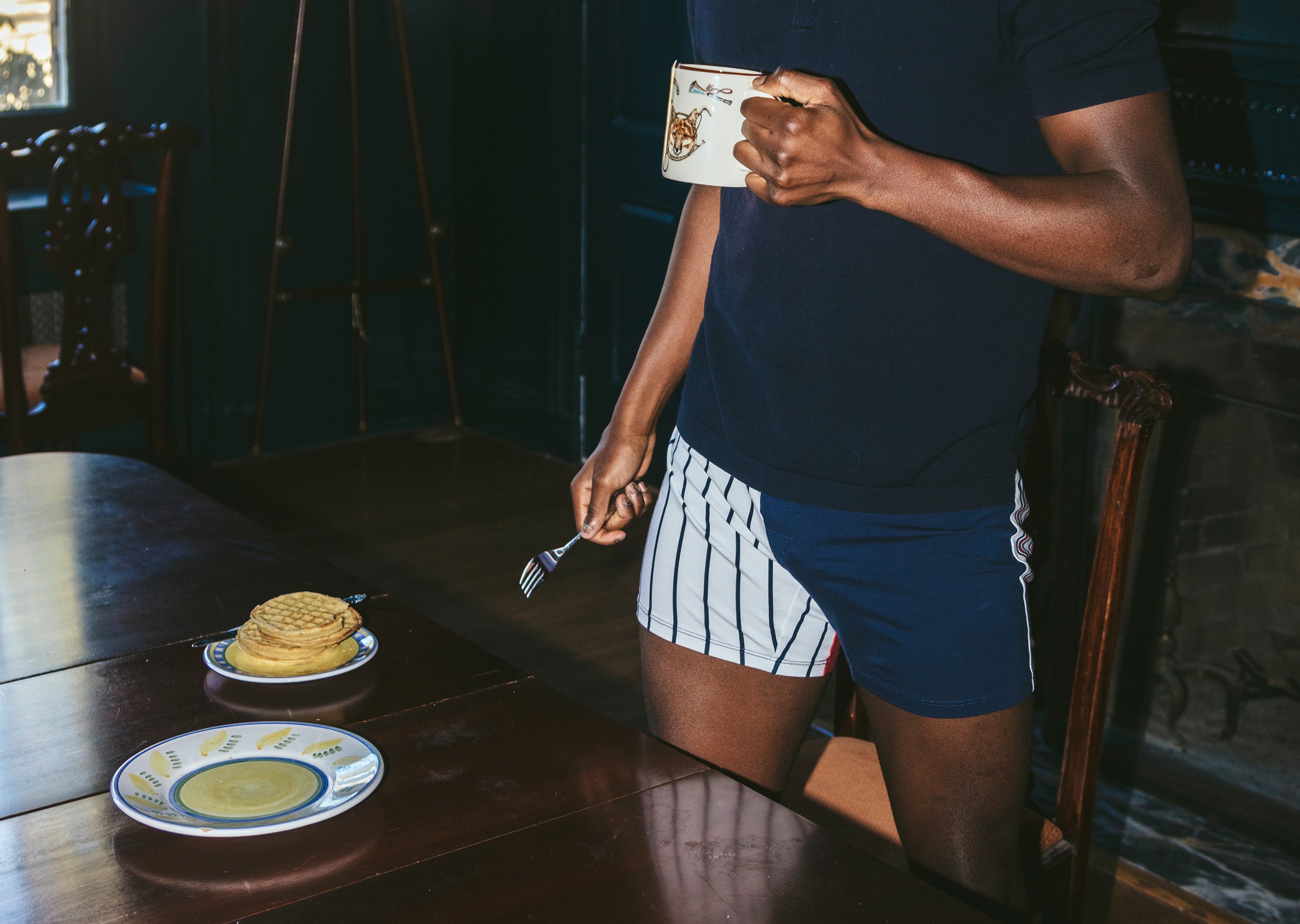 Close up shot of man holding a coffee mug wearing blue shirt and red/white/blue stripe Regatta slim fit boxer.