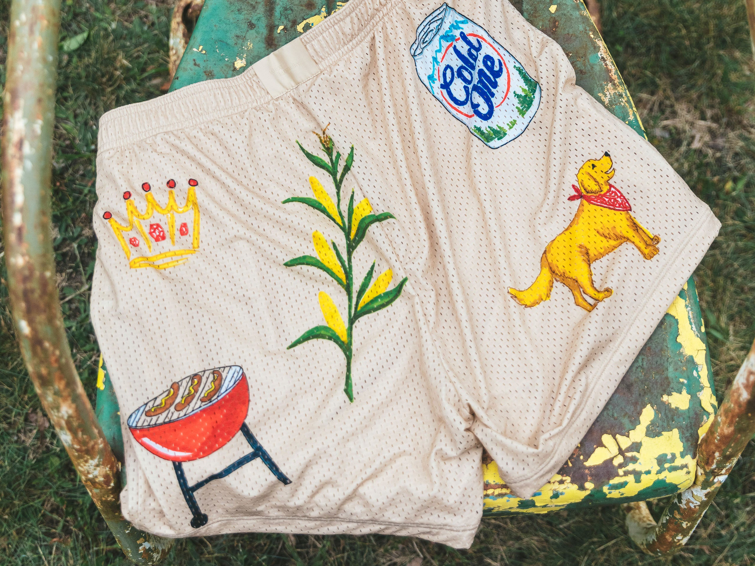 Back side of senior cord beige lounge short. This side shows dog, crown, grill, plant and beer can.