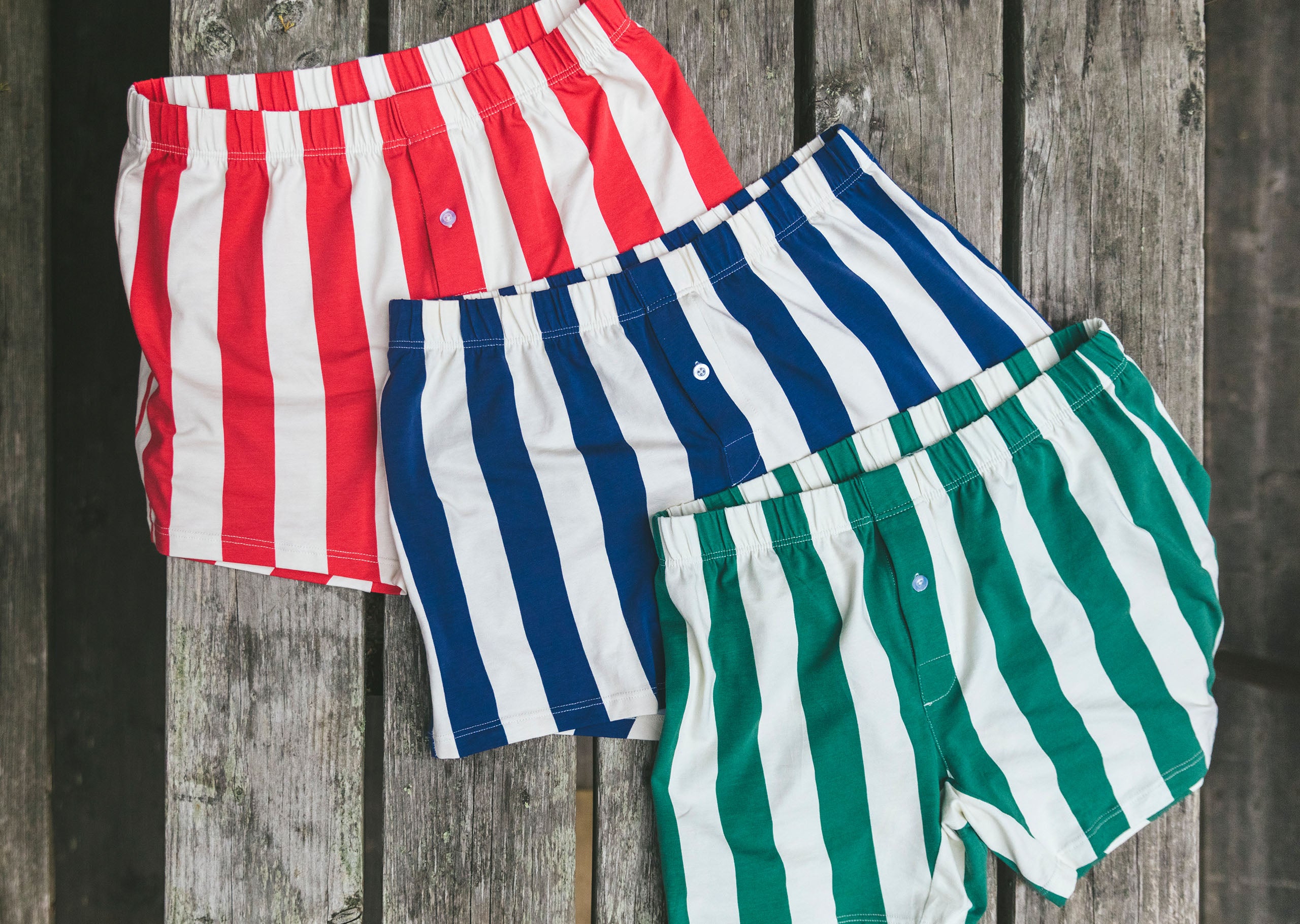 3 pairs of stripe slim fit boxers laid on a wooden background. Navy, red and hunter green.