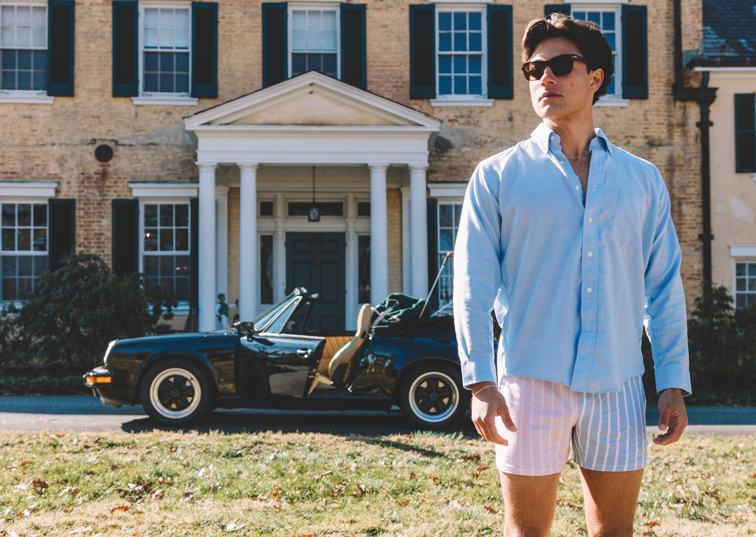 Man standing in front of a house and car wearing Pastel Stripe slim fit boxers and blue dress shirt.