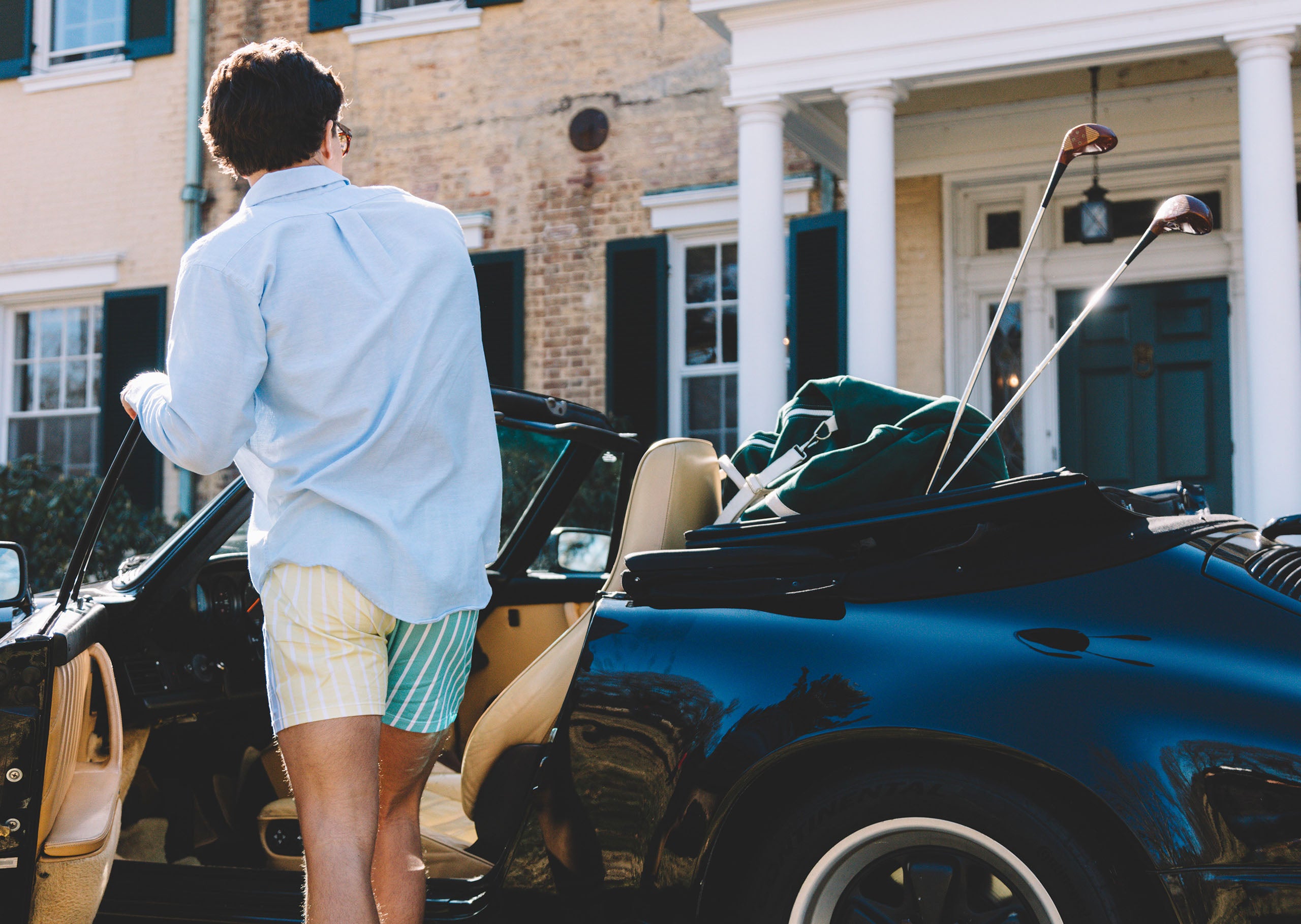 Man wearing blue dress shirt and pastel stripe slim fit boxers getting into a car.