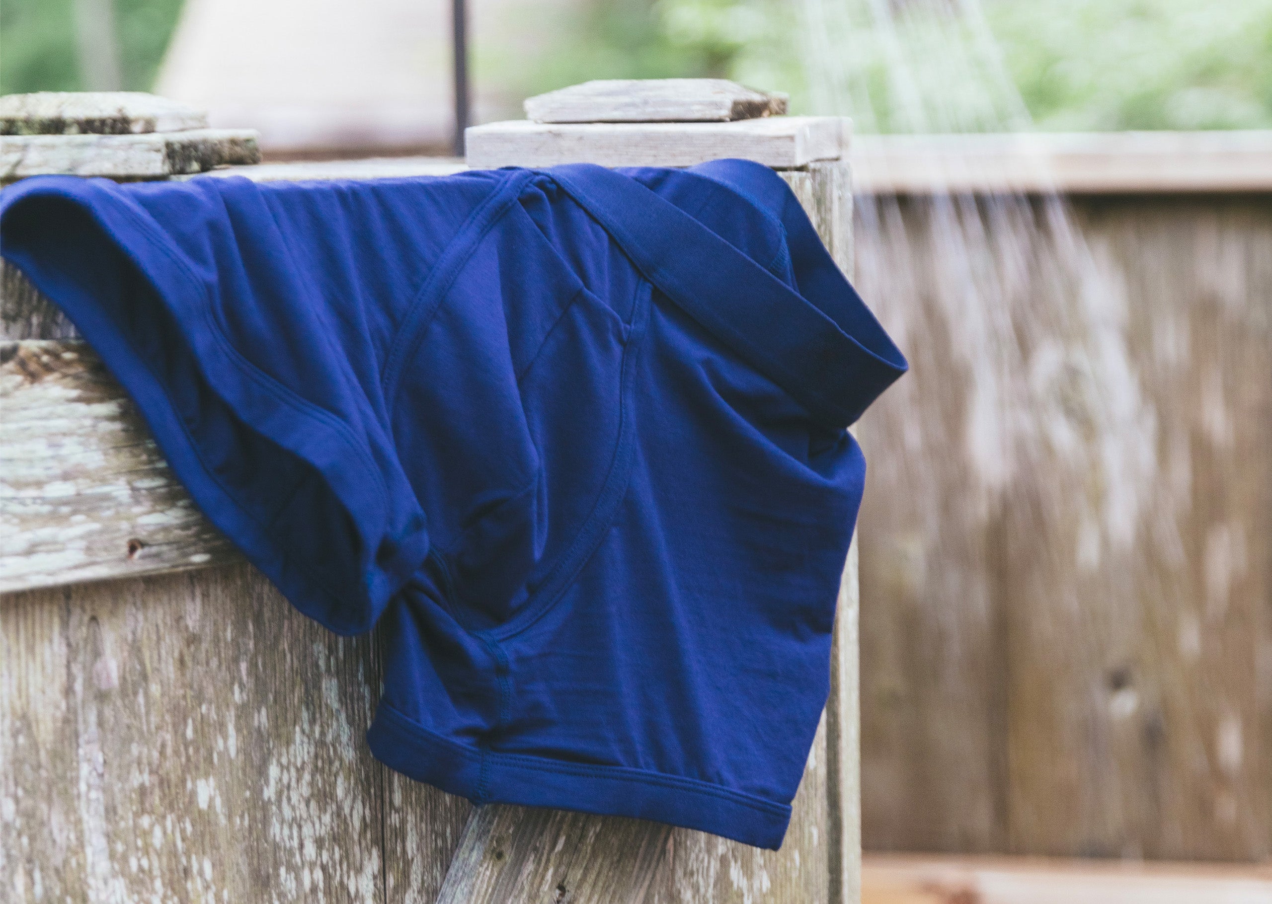 Pair of blue boxer briefs sitting on the sider of an outdoor shower.
