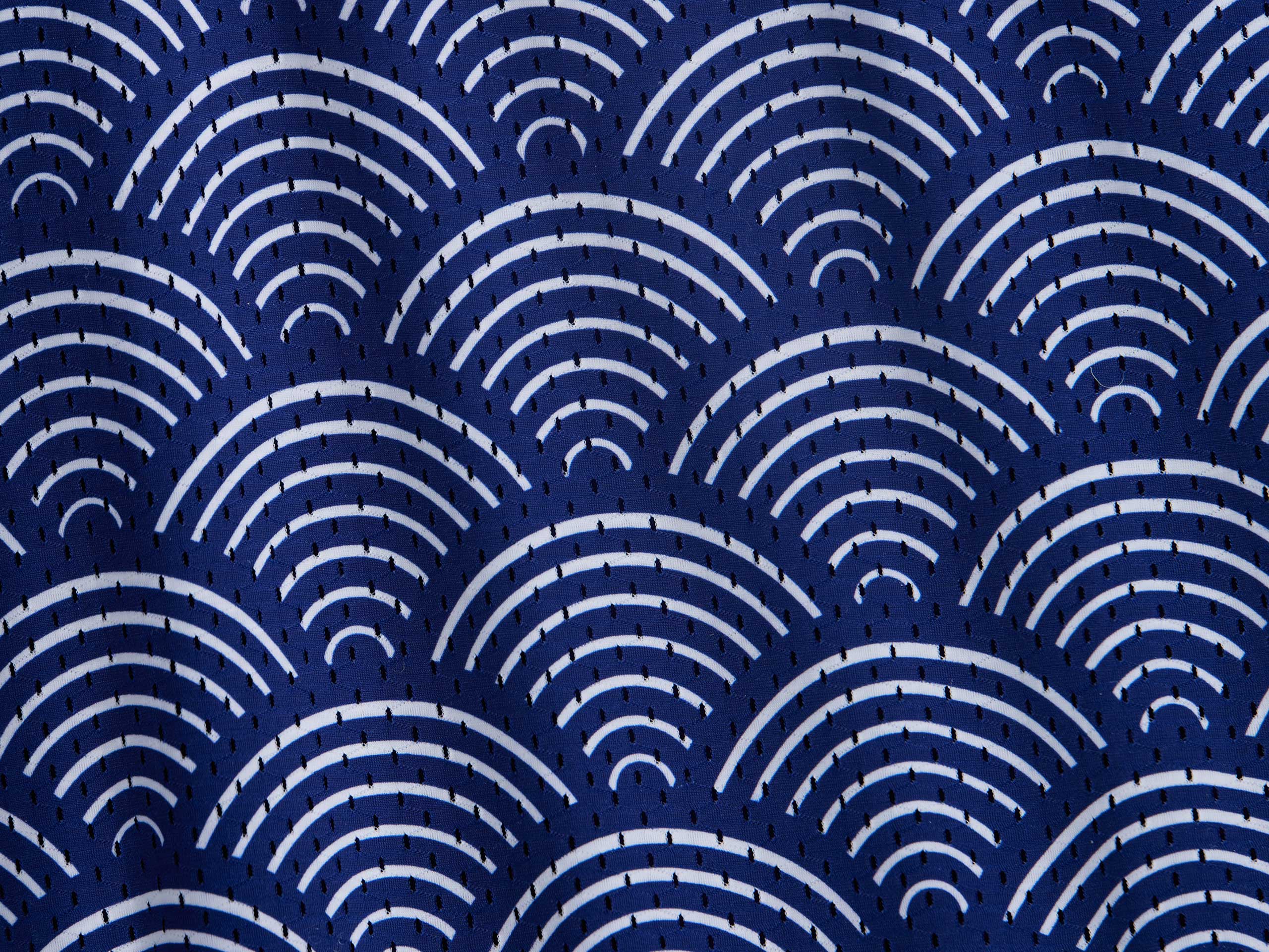 Close up detail shot of mesh material from blue lounge shorts with sunrise pattern.