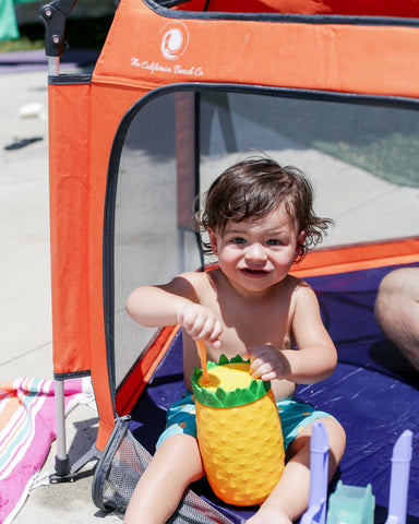 Little boy sitting inside the Pop N Go playpen outside 