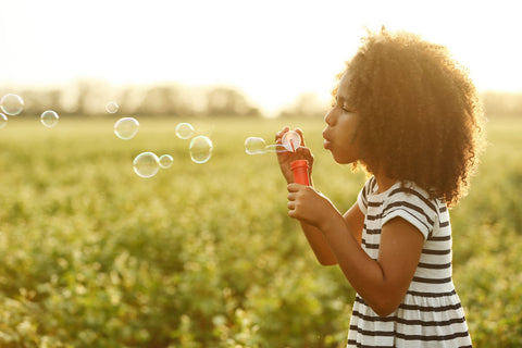 Child blowing bubbles in the middle of a field