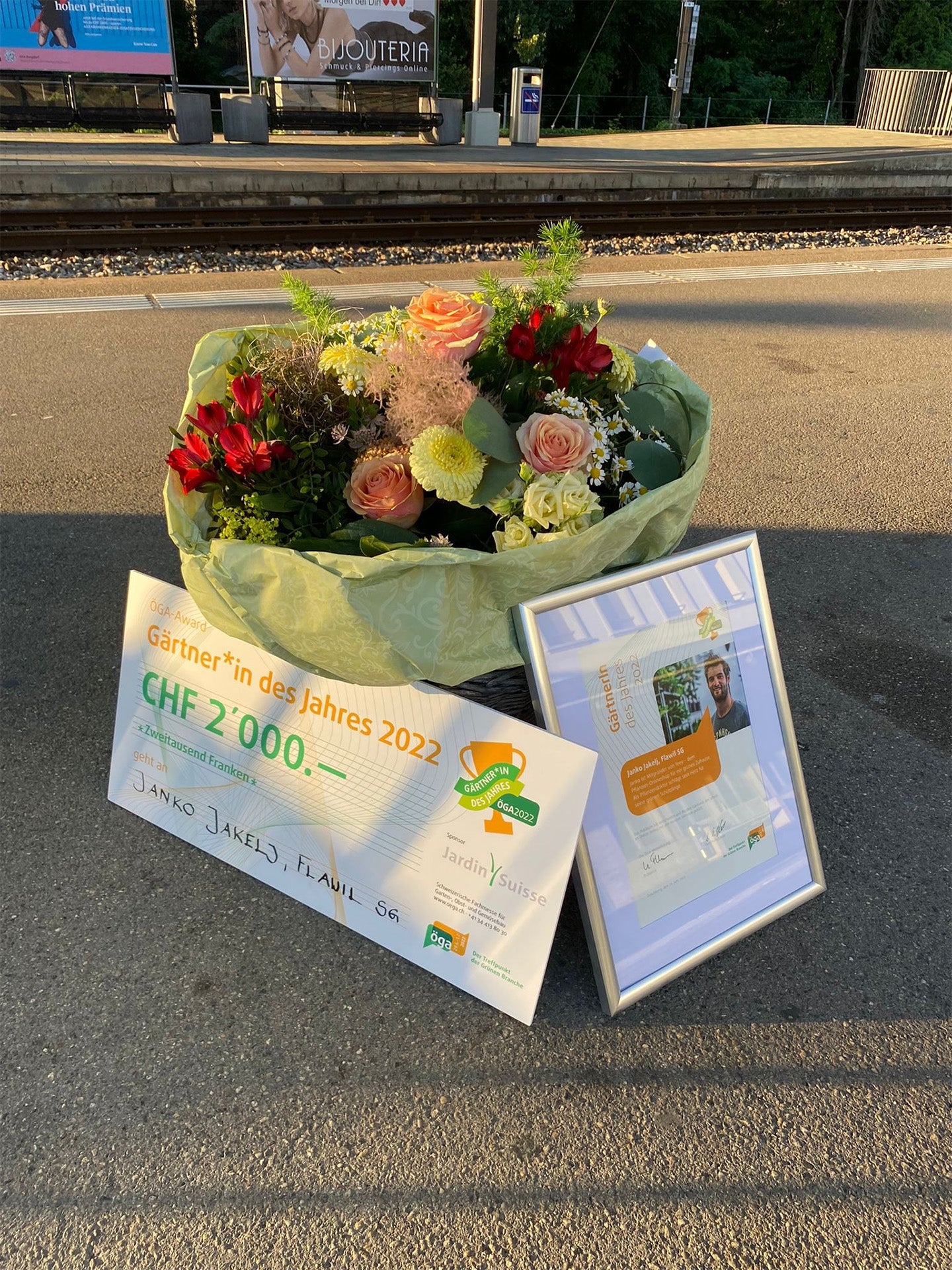Bild eines Blumenstrausses und eines grossen Gutscheins: Auszeichnung Janko für Gärtner des Jahres.