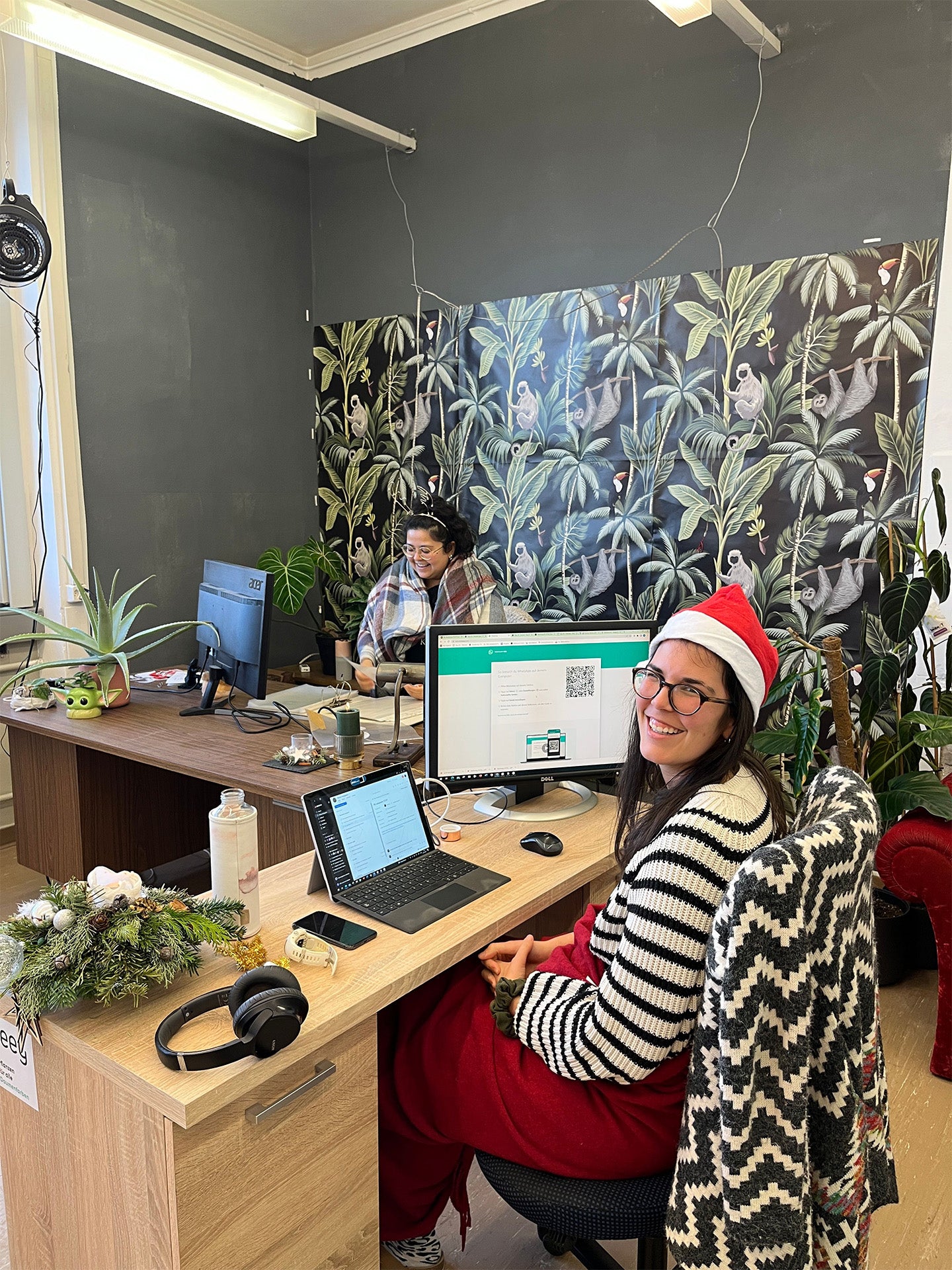 Mona und Macy sitzen in einem bunten Büro mit bunter Tapete.