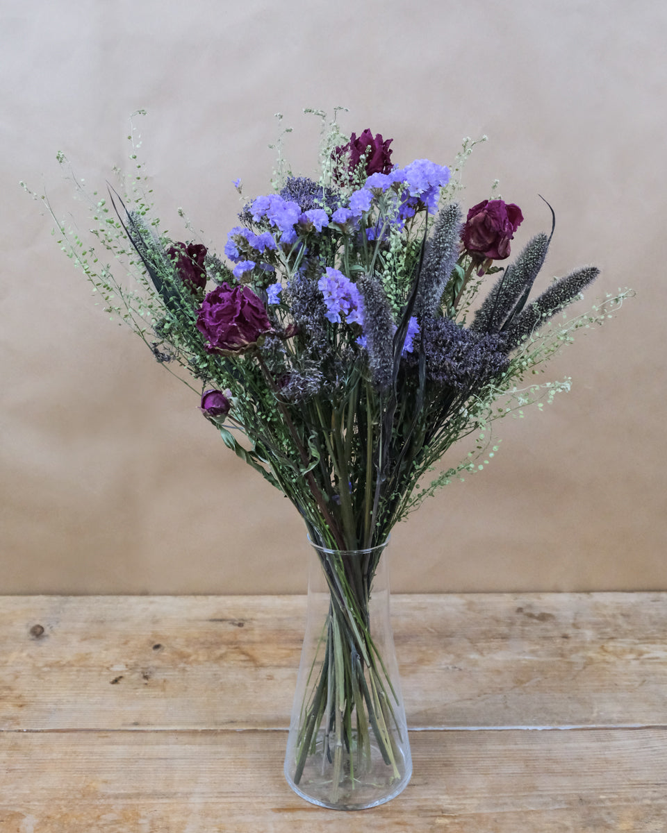 Utuon-Trockenblumen-Strauss mit violetten und burgunderroten Blüten in transparenter Vase