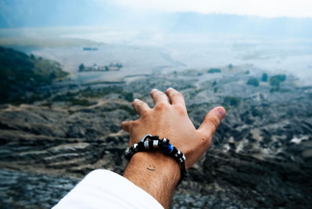 Jason standing in front of Bromo Crater wearing his El Camino travel souvenir Bracelet.