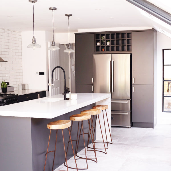 Trio of glass pendants over a grey kitchen shaker island