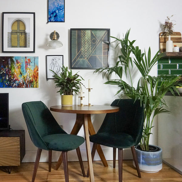 Gallery wall with glass wall light and green velvet chairs