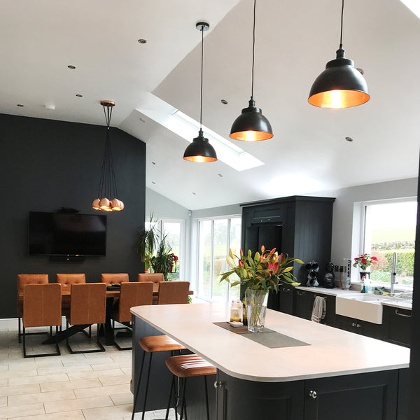 Open plan dark kitchen interior with industrial pendants