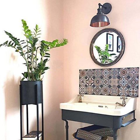Pink bathroom decor with standing plant, patterned splashback tiles and vintage wall light