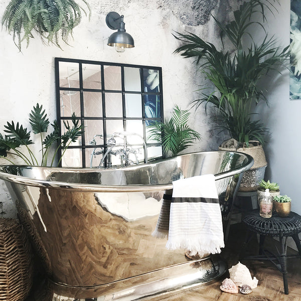 Concrete bathroom interior with chrome bath, greenery and waterproof wall light