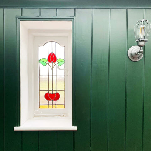 Green panelled wall with stained glass window and industrial wall light