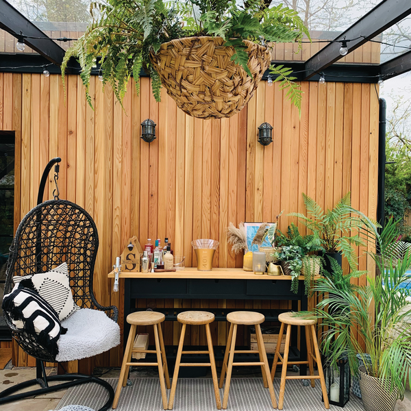 A wooden outdoor bar with stools and industrial lighting