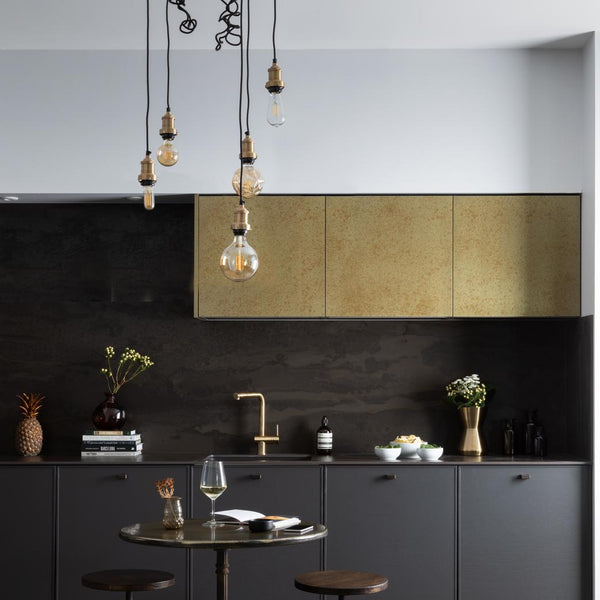 A dark industrial style kitchen with exposed wire lights 