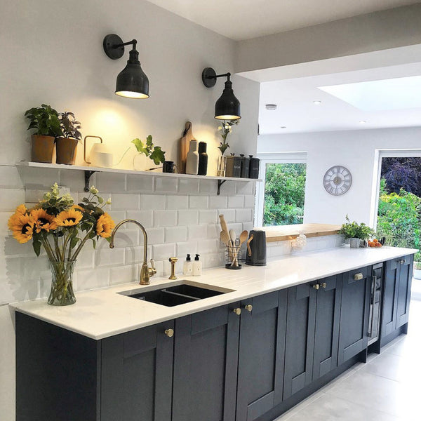 A kitchen with black cabinets and industrial wall lights