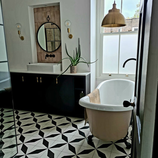 A bathroom with pink wall tiles and black and white tiled flooring