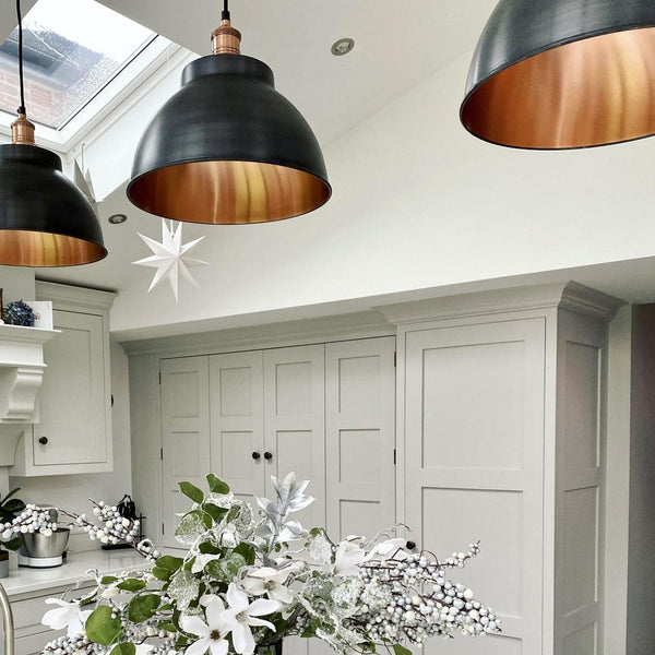 Three pewter and brass industrial pendant lights in a kitchen 