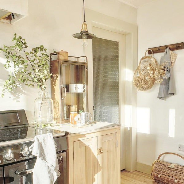 A well lit kitchen with a pendant handing over a surface