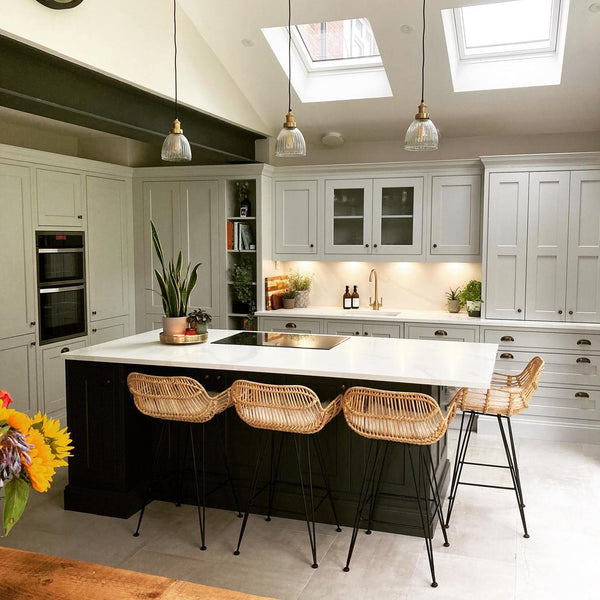 A kitchen with high ceilings and thress glass pendants over a kitchen island