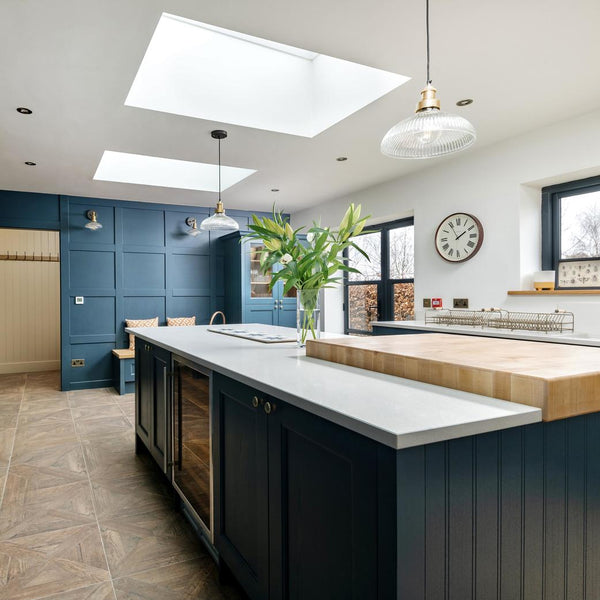 A kitchen with blue cabinets and glass pendants