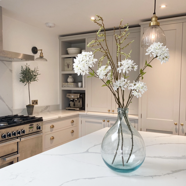 A white kitchen with a vase of flowers