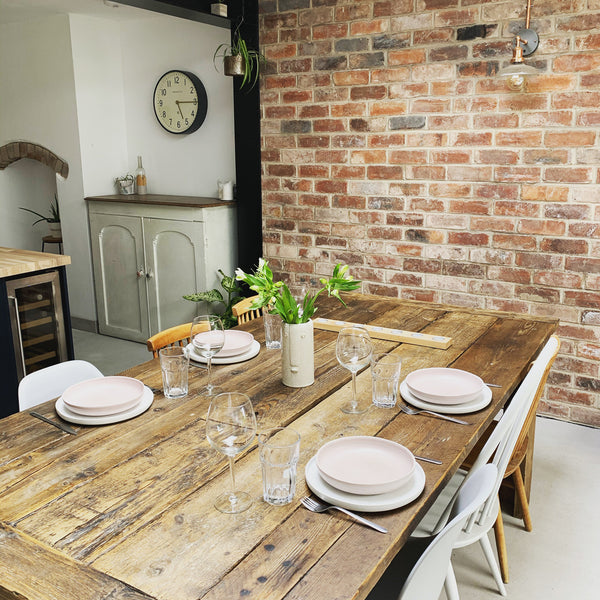 A rustic dining table next to an exposed brick wall