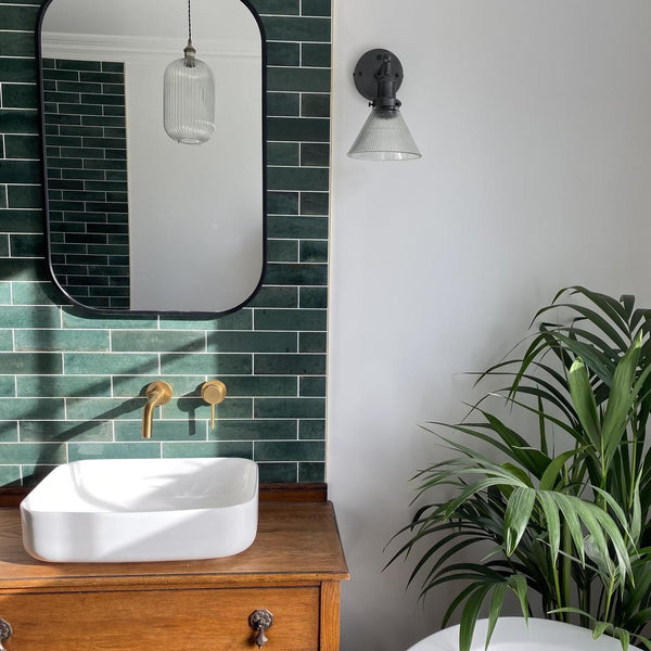 A green-tiled bathroom with a houseplant