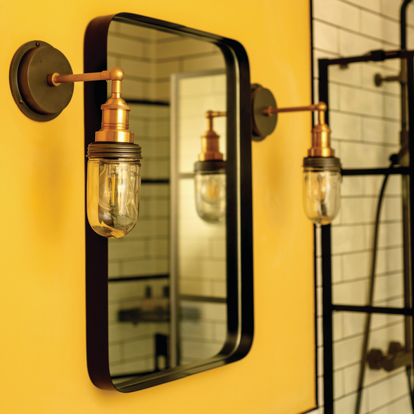 A bright yellow bathroom with gold light fixtures