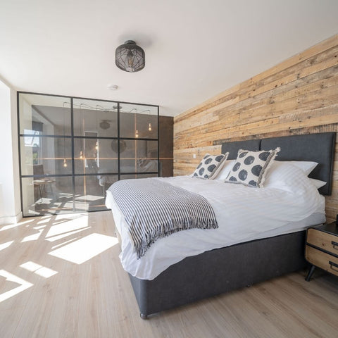 An open, modern bedroom with sunlight from large windows