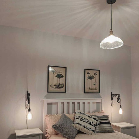 A glass pendant light hanging in a white bedroom