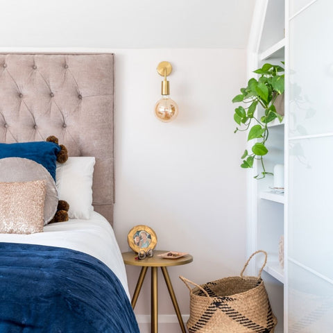 A pastel-coloured bedroom with plant and brass light by Industville